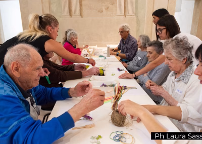 Laboratorio creativo intergenerazionale con anziani e operatori museali seduti attorno a un tavolo